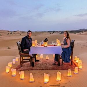 The Desert Safari Jaisalmer في Sām: يجلس رجل وامرأة على طاولة في الصحراء