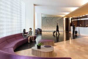 two people sitting on a couch in a lobby at Courtyard by Marriott Shin-Osaka Station in Osaka
