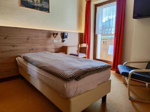 ein Schlafzimmer mit einem Bett, einem Stuhl und einem Fenster in der Unterkunft Albergo Pensione Sport in Arabba