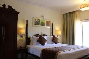 1 dormitorio con 1 cama grande con sábanas y almohadas blancas en Evershine Resort & Spa, en Mahabaleshwar