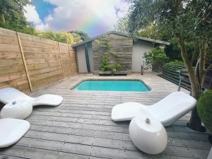 a swimming pool with two white chairs next to a fence at Baha Sanctuary Villa - 2 Bedroom Pool Villa in Plettenberg Bay