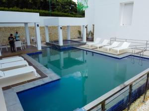 a pool with white chairs and blue water at 1Br Apartment at Ocean Garden Villas, Boracay Newcoast in Boracay