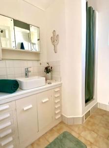 La salle de bains blanche est pourvue d'un lavabo et d'un miroir. dans l'établissement Charmant haut de villa T3, à Saint-Cyr-sur-Mer
