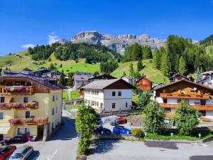 ein Dorf in den Bergen mit parkenden Autos in der Unterkunft Albergo Pensione Sport in Arabba