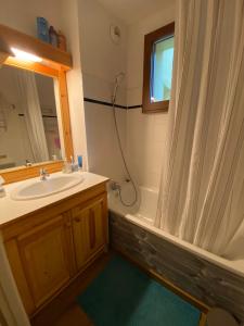 ein Badezimmer mit einem Waschbecken, einer Badewanne und einer Dusche in der Unterkunft Chalet Jonquille in Valfréjus