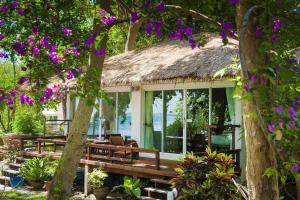 a house with a thatched roof with purple flowers at Larissa Samed resort in Ko Samed