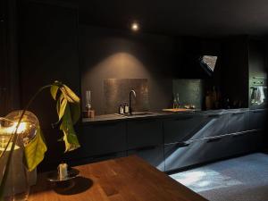 una cocina con armarios negros, fregadero y mesa en The Lodge, en Mölnlycke