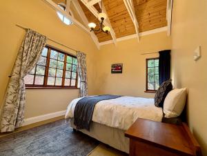 a bedroom with a bed and a table and windows at Touchstone Cottage in Hilton