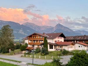 eine Gruppe von Gebäuden mit Bergen im Hintergrund in der Unterkunft Hotel AlpIn Bed & Breakfast in Fischen im Allgäu