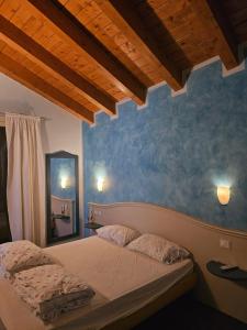 a bedroom with a bed with a blue wall at Via Fantoni 4 in Castione della Presolana