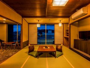 加賀的住宿－Yukai Resort Saichoraku，客厅配有桌椅和电视。