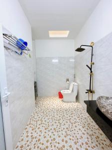 a white bathroom with a toilet and a shower at Ahome in Buôn Ðũng