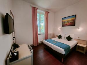 ein Hotelzimmer mit einem Bett und einem TV in der Unterkunft Will's Hotel in Narbonne