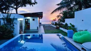 a swimming pool in front of a house with a sunset at RLJ Beach House in Naval