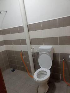 ein Badezimmer mit einem WC und einem orangefarbenen Schlauch in der Unterkunft MinAn Homestay Gua Musang (no tv no wifi) in Gua Musang