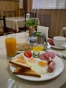 a breakfast plate with eggs sausage and toast and a glass of orange juice at Belon Land in Astana