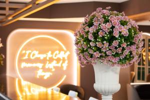 eine weiße Vase voller rosa Blumen auf dem Tisch in der Unterkunft Siri Grand Bangkok Hotel in Bangkok