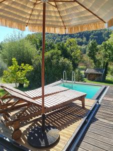 una terraza de madera con sombrilla junto a la piscina en Chambre dans chalet avec piscine, en Saint-Jean-en-Royans