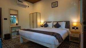 a bedroom with a large white bed with two lamps at Whiteflower Cottages Vagator in Vagator