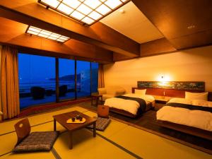 a bedroom with two beds and a large window at Yukai Resort Premium Hotel Ranpu in Hirado