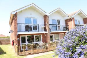 a house with a balcony and purple flowers at Corton Retreats At Waterside Park in Corton