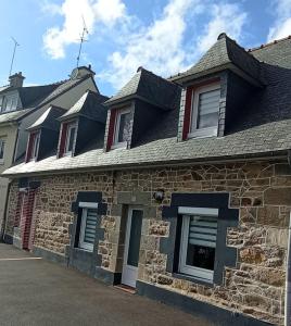 een stenen huis met blauwe ramen en een dak bij Gite entre Paimpol et Erquy. Proche palais des congrès in Ploufragan