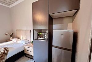 een kleine slaapkamer met een koelkast naast een bed bij La Creme Waterkloof 2 in Pretoria