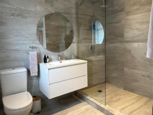 a bathroom with a toilet and a sink and a mirror at Whispering Oaks Guest House in George