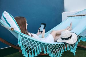 a woman laying in a hammock while holding a cell phone at HD Acuario Lifestyle in Las Palmas de Gran Canaria