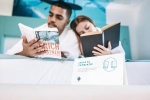 un hombre y una mujer leyendo libros junto a una caja en HD Acuario Lifestyle, en Las Palmas de Gran Canaria