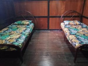two beds sitting in a room with wooden walls at Azli homestay in Tampin