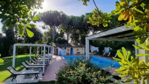 a pool with lounge chairs next to a house at Is Benas Country Lodge in San Vero Milis