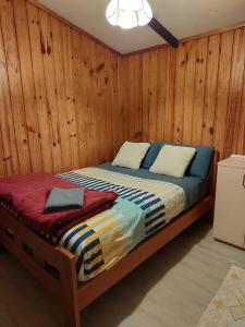 een bed in een kamer met een houten muur bij Sister’s place in Auckland