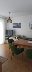 ein Wohnzimmer mit einem Holztisch und grünen Stühlen in der Unterkunft Wunderschöne Ferienwohnung direkt an der Elbe, Alt-und Neustadtnähe in Dresden
