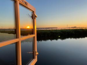 uma vista para o pôr-do-sol a partir da janela de uma casa em Zelfstandig appartement - 10 minuten tot Amsterdam em Ilpendam