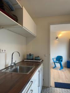 cocina con fregadero y silla azul en Zelfstandig appartement - 10 minuten tot Amsterdam, en Ilpendam