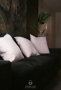 a black couch with four white pillows on it at Spa Niagara privé avec jacuzzi in Herstal