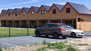 two cars parked in a parking lot in front of a building at Domki NA PNIU in Jarosławiec