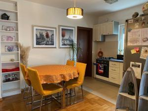 a kitchen with a dining room table and yellow chairs at Apartman Fenjer in Zagreb