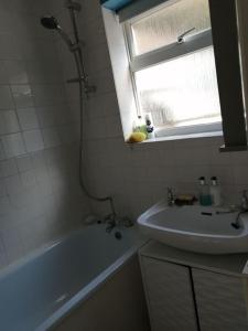 a bathroom with a tub and a sink and a window at Seaside 2 bed terraced house with garden in Hastings