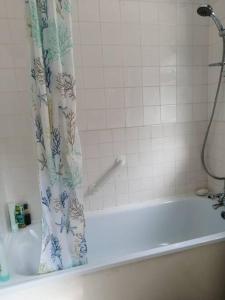 a bath tub with a shower curtain in a bathroom at Seaside 2 bed terraced house with garden in Hastings +12 photos
