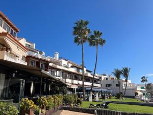 a row of buildings with palm trees in the background at Playa del Duque-Amazing views 2 bedroom in Adeje