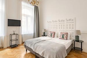 a white bedroom with a bed and a flat screen tv at House Beletage-Boutique in Budapest