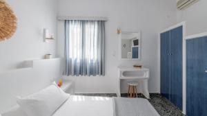 a white bedroom with a bed and a sink at Agia Kyriaki Studios in Agia Kiriaki Beach