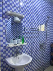 Baño de azulejos azules con lavabo y espejo en Ulili 1br apts Makepe, en Douala