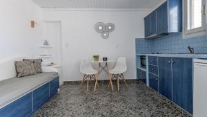 a kitchen with blue cabinets and a table and chairs at Agia Kyriaki Studios in Agia Kiriaki Beach