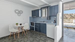 a kitchen with blue cabinets and a table and chairs at Agia Kyriaki Studios in Agia Kiriaki Beach +37 photos