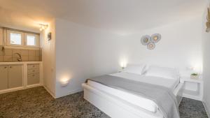 a white bedroom with a white bed and a sink at Agia Kyriaki Studios in Agia Kiriaki Beach