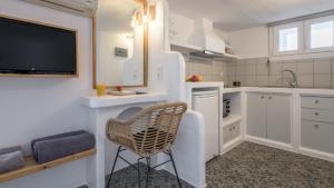 a kitchen with a chair and a tv on a wall at Agia Kyriaki Studios in Agia Kiriaki Beach