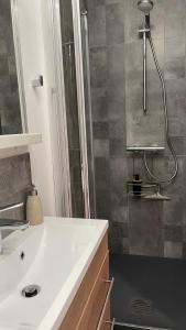 La salle de bains est pourvue d'une douche et d'un lavabo blanc. dans l'établissement Suite Rêve - SDB WC Privatif - Entrée autonome - Grande TV NETFLIX, à Compiègne